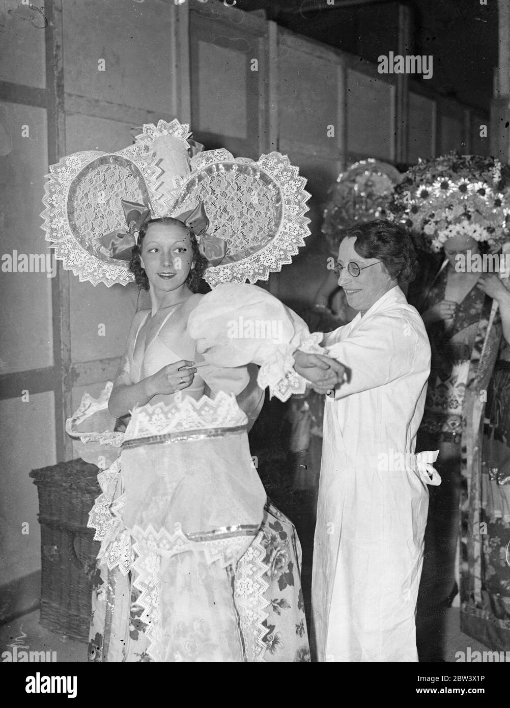 Behind The Scenes At Radio Olympia Theatre . Photo shows : Nan Wealden , one of the Gordon Ray Girls , putting on an elaborate dress before appearing in the variety show at the National Radio Exhibition , Olympia . 26 August 1936 Original caption from negative Stock Photo