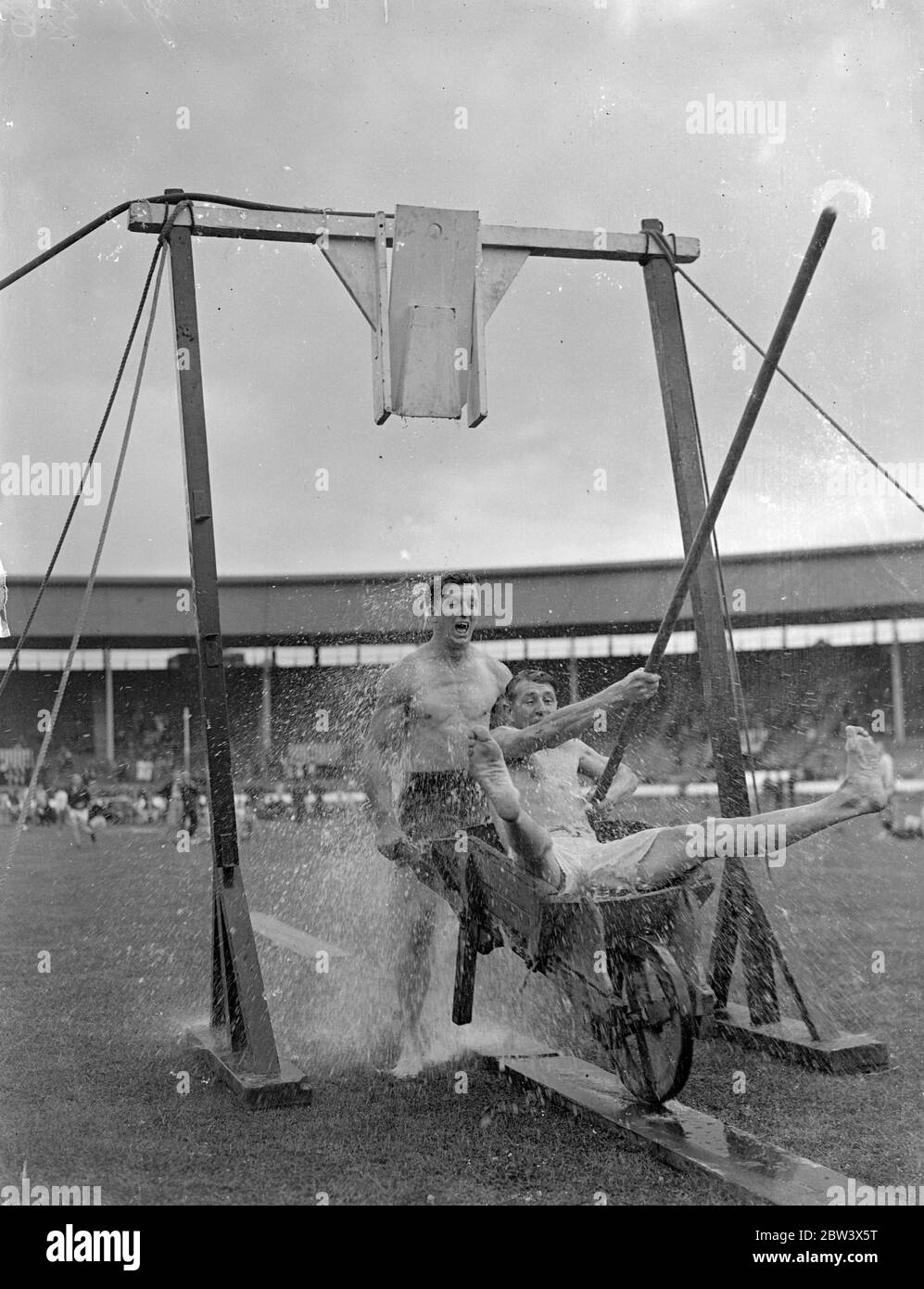 Tilting the bucket at firemen ' sport . The thirty fourth annual athletic meeting of the London Fire Brigade Athletic Association was held at the White City stadium . Photo shows , Mr T S Gibbons of the Southwark ( wheeling barrow ) and Mr G S Rudeun of Whitefriars competing in the Tilting the bucket event . 22 August 1936 Original caption from negative Stock Photo