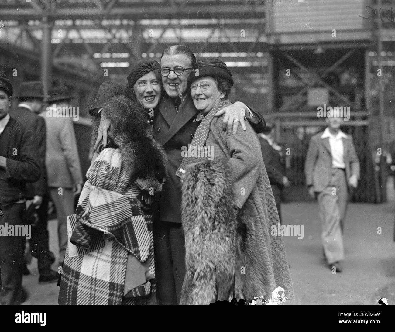 Woolsey , of Wheeler and Woolsey , welcome his wife and mother to London . Robert Woolsey , of Wheeler and Woolsey , the film comedian , was at Waterloo Station to welcome his wife and mother when they arrived on the ' Normandie ' boat train from America . Photo shows , Robert Woolsey , smoking a cigar as usual , with his wife , and mother on their arrival at Waterloo . 24 August 1936 Original caption from negative Stock Photo