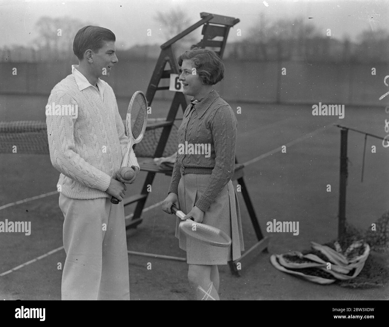 R C Nicoll, the 16-year-old Middlesex lawn tennis player, who distinguished himself in the Herga' Club's tournament at Harrow against H W Austin, has accepted Austin's invitation to play with him on the men's doubles in the Hardcourt championship at Bournemouth. Nicoll's schoolmaster has specially let him off for the week of the tournament. Photo shows R C Nicoll with his sister Jean Nicoll a the Herga Club, Harrow, today. 27th March 1937 Stock Photo