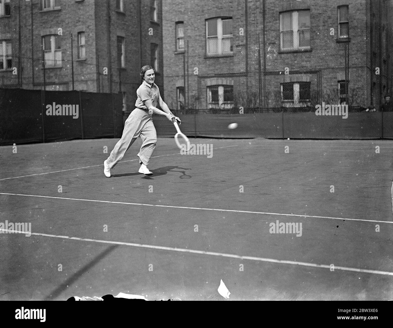 Mary Heeley plays in trousers. Defeats Miss Pope in Paddington Tournament. Miss Mary Heeley, gave Miss Dorothy Round a close fight in the final of the Hergan Club Tournament, defeated Mr Pope in the Paddington Tennis Tournament at Paddington Club. Photo shows: this Mary Heeley, wearing trousers, in play against Miss Pope. 31 March 1937 Stock Photo