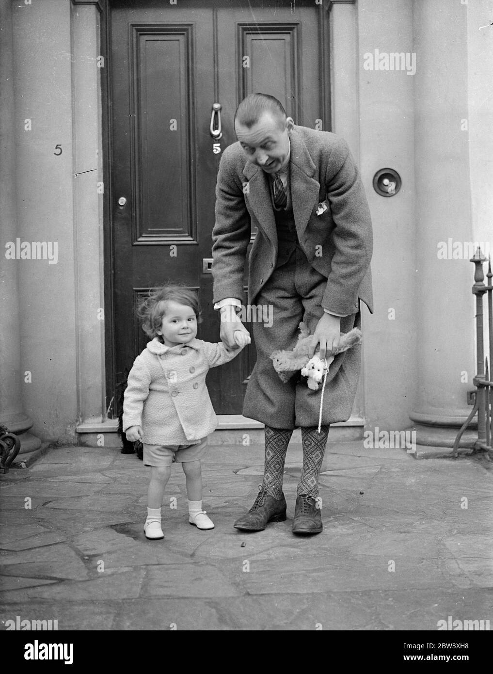Good Friday was the second birthday of Viscount Dupplin, son of Lord and Lady Kinnoull. The little Viscount celebrate the anniversary by playing games with his father and two older sisters, Lady Vanetia and Lady June Hay, in the garden of their home at Regents Park. Photo shows: the Viscount Dupplin, aged two, with his father, Lord Kinnoull. 26th March 1937 Stock Photo