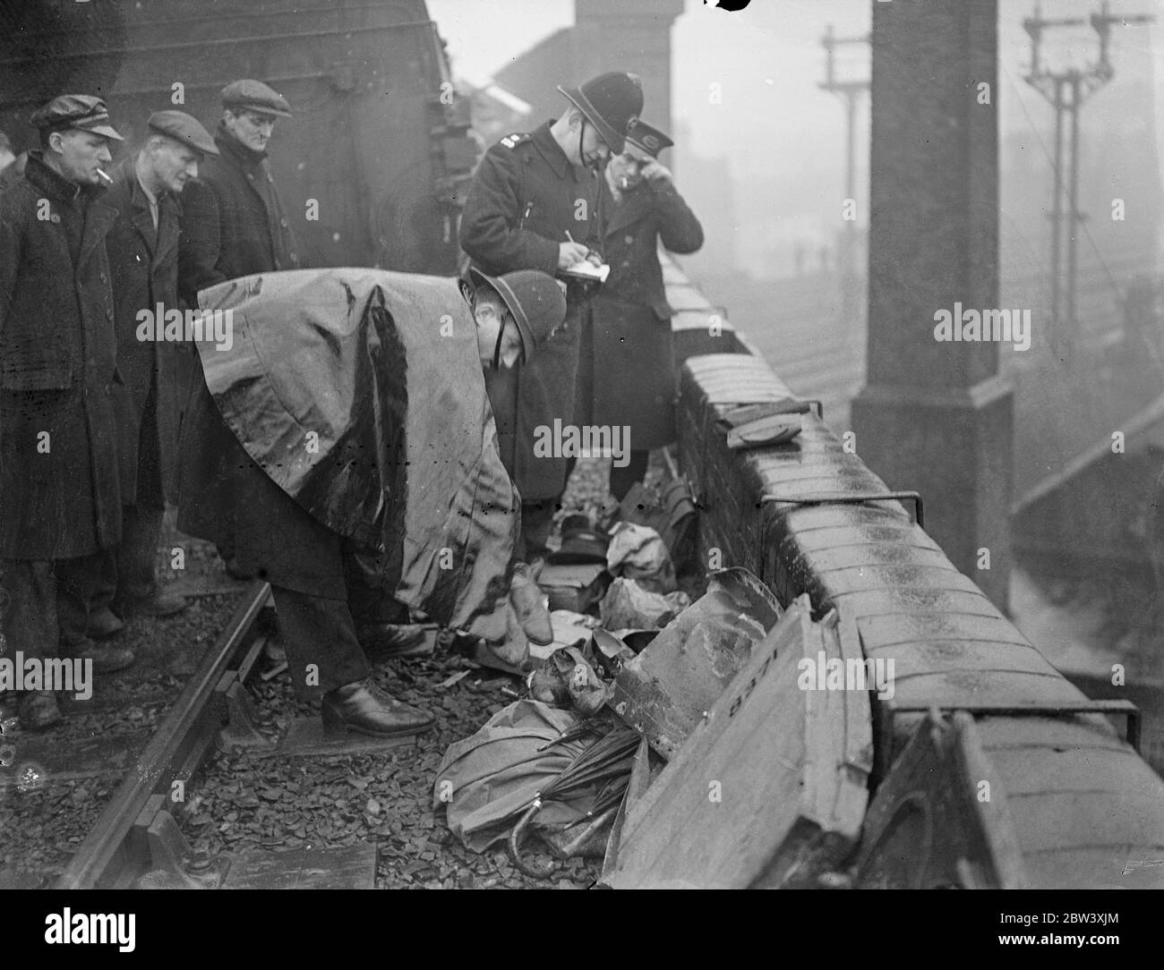 12 people were killed and nearly 50 injured when the electric trains collided head-on at Fourspan Bridge between Queen's Road and Battersea Park Station. Coaches were telescoped and overturned. Photo shows: Policemen checking over the property of injured passengers at the scene of the crash. 2 April 1937 Stock Photo