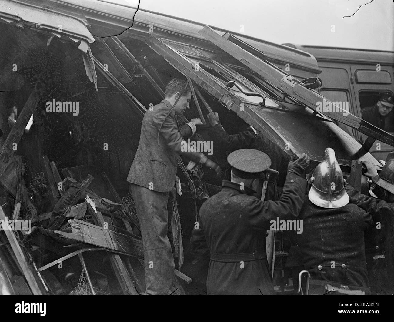 12 people were killed and nearly 50 injured when the electric trains collided head-on at Fourspan Bridge between Queen's Road and Battersea Park Station. Coaches were telescoped and overturned. Photo shows: Police and firemen at work amid the wreckage. 2 April 1937 Stock Photo