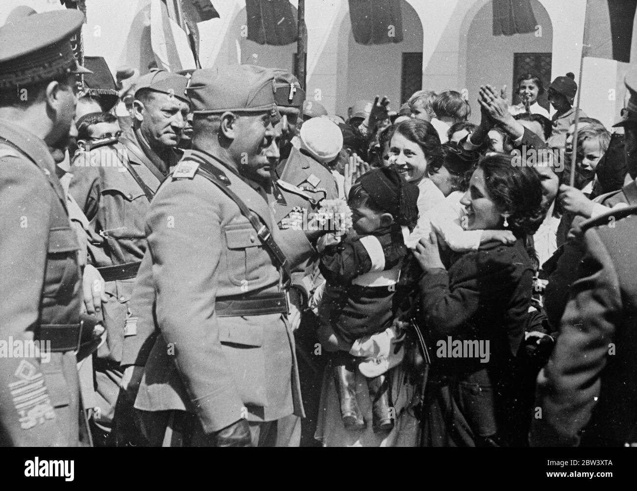 Libyan colonists bask in Duce ' s smile . Signor Mussolini relaxes his usually stern features in a smile when he chats with women settlers and their children at the Luigi Razza colony during his journey through Libya . 17 March 1937 Stock Photo