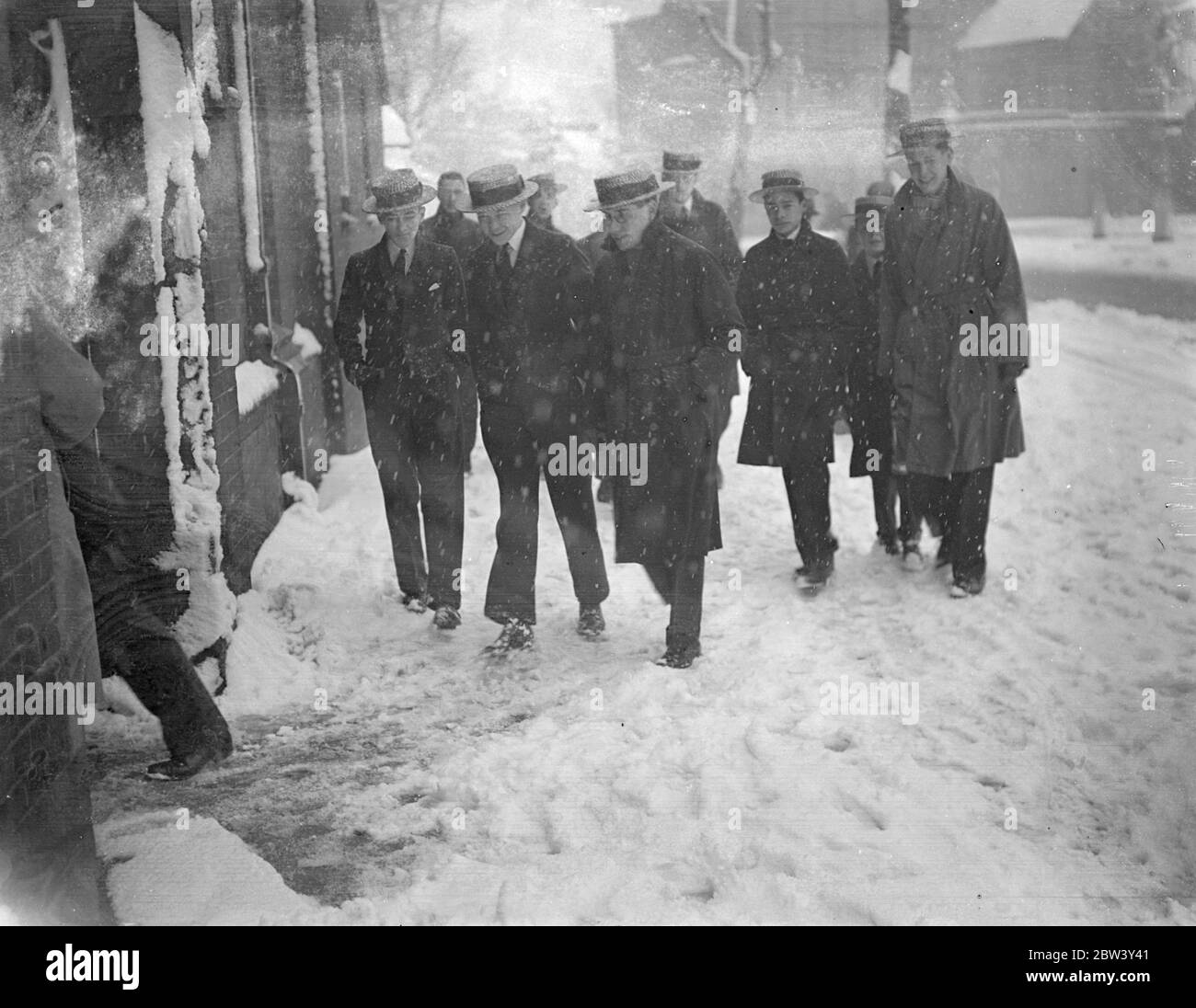 Straw hats in the snow . A peculiar contrast in the snow as the straw hatted schoolboys walked through the white streets of Highgate in London ' s heavy snow storm today . ( Sunday ) . 7 March 1937 Stock Photo