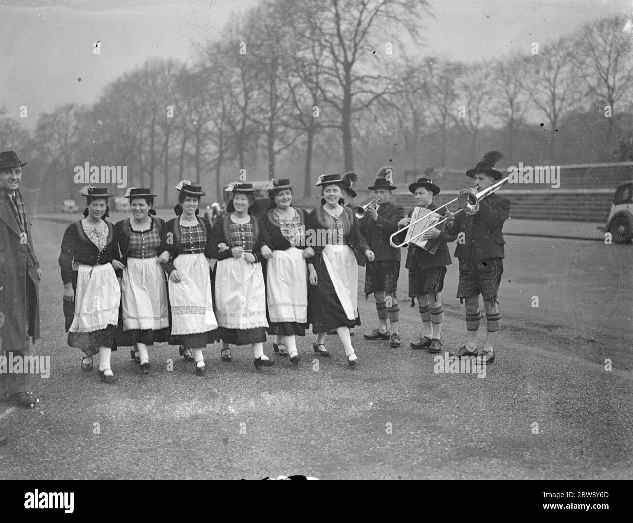 Bavarian peasants play mountain music in Kensington Gardens . A party of Bavarian Schuhplattlers from the Bavarian Alps are performing at the Polytechnic Tours Reunion , Royal Albert Hall . This is their first visit to London . Photo shows , girl members of the party rehearse to the music of their own band in Kensington Gardens . 6 March 1937 Stock Photo