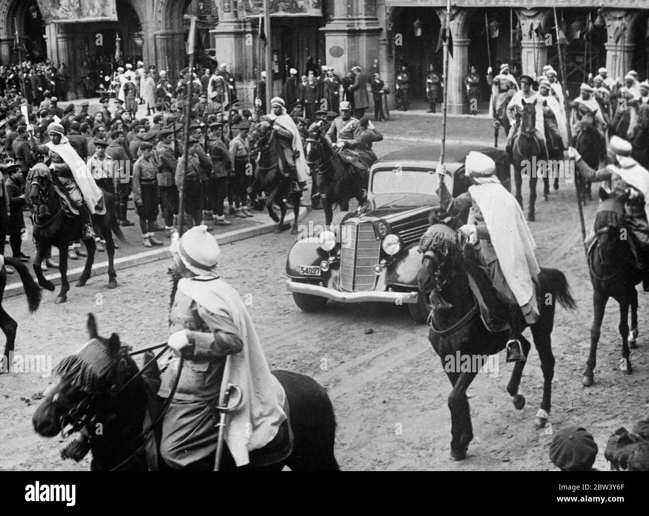 Franco and Moorish cavalcade pass through Salamanca . Escorted by his specially selected Moorish bodyguard , who on horseback , General Franco , head of the insurgents Spanish Government , drove through Salamanca to receive the credentials of the German Ambassador , General Faupel , at the City Hall . The streets of the city were filled with huge crowds , spectators watching even from the balconies of buildings . Photo shows , the Moorish bodyguard surrounding General Franco ' s car as he passed through crowded Salamanca . 9 March 1937 Stock Photo