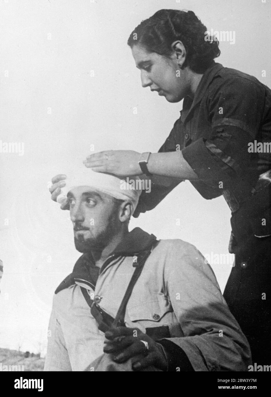 First aid behind the rebel lines . A nurse expertly bandages the head of a wounded member of the Phalangists ( Fascist ) corps attached to Franco ' s rebel troops , at a first aid post behind the lines after a rebel attack to the south of Madrid . 8 March 1937 Stock Photo