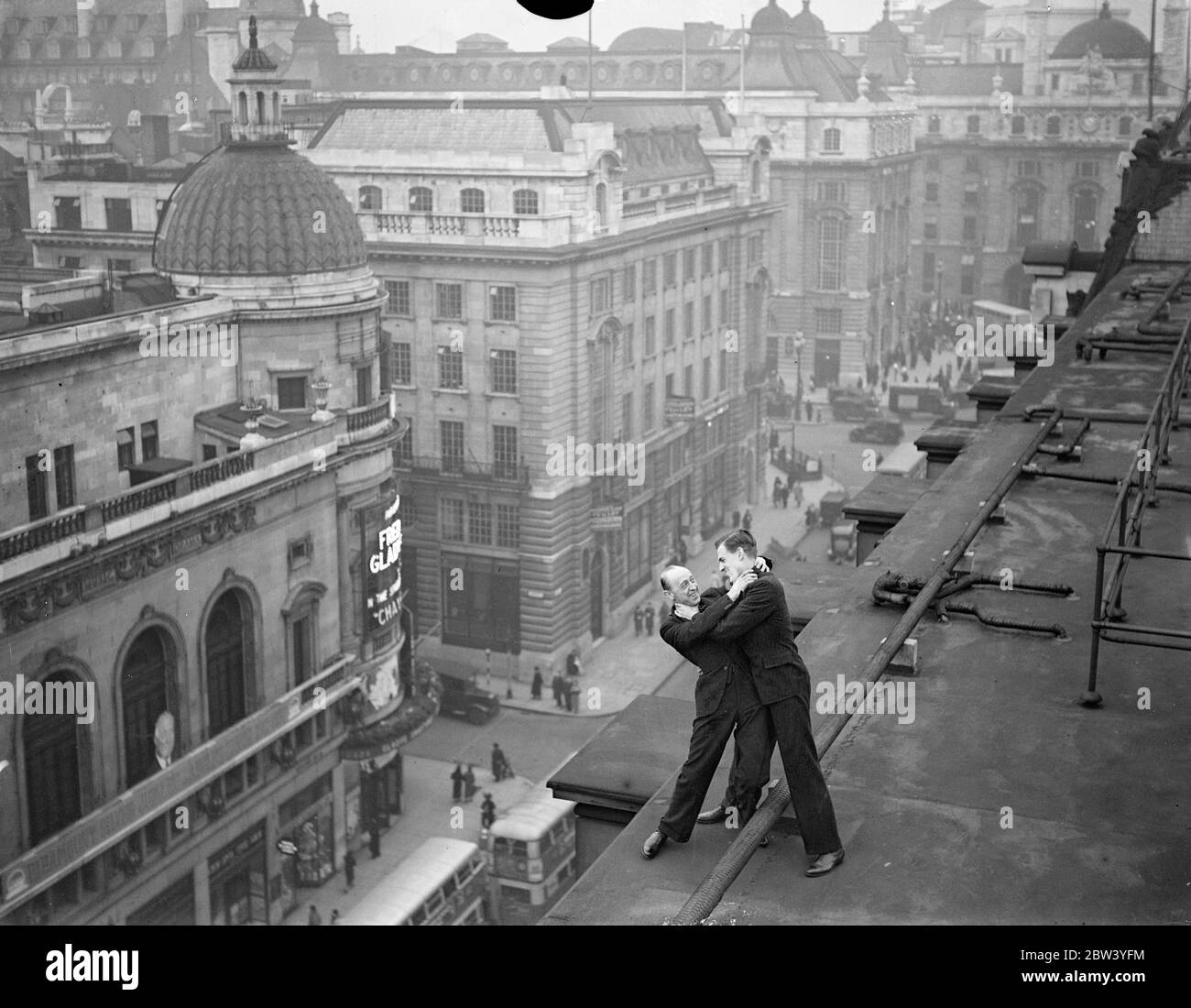 Death duel over Regent Street . With death waiting 100 feet below , two men wrestle desperately for supremacy on the edge of the roof overlooking busy Regent Street , London . They are Ronald More , ( left ) and Anthony Hastings , two members of filmland ' s first ' Suicide Squad ' rehearsing thrills for Britain's film public . With the motto ' No Risk to Big ' squad has been formed with the object of banding together the ' stunt ' men and women of the film studios . They are pledged never to refuse a ' stunt ' , however the danger . 9 February 1937 Stock Photo