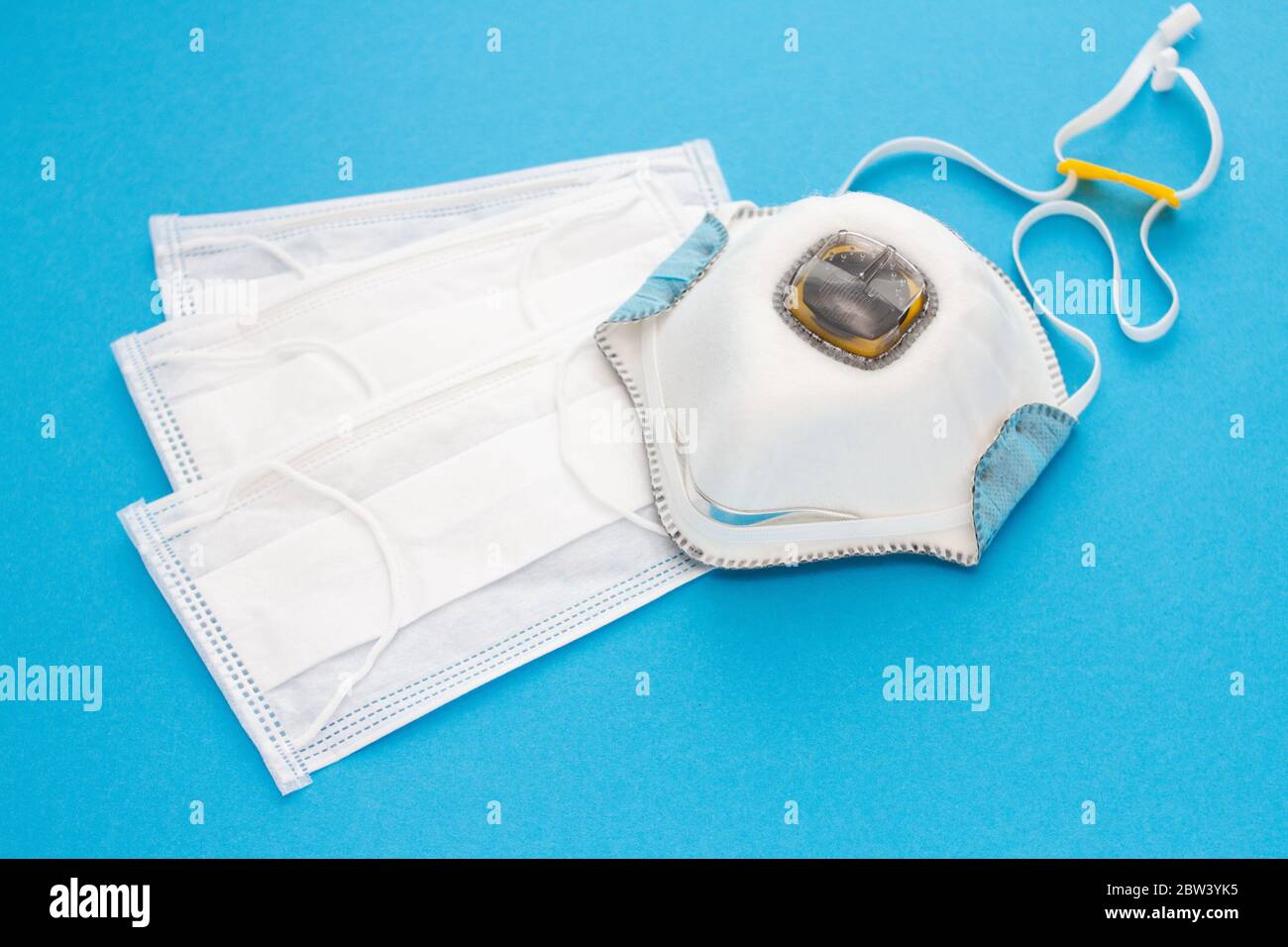 set of medical masks and a respirator for personal protection on a blue ...