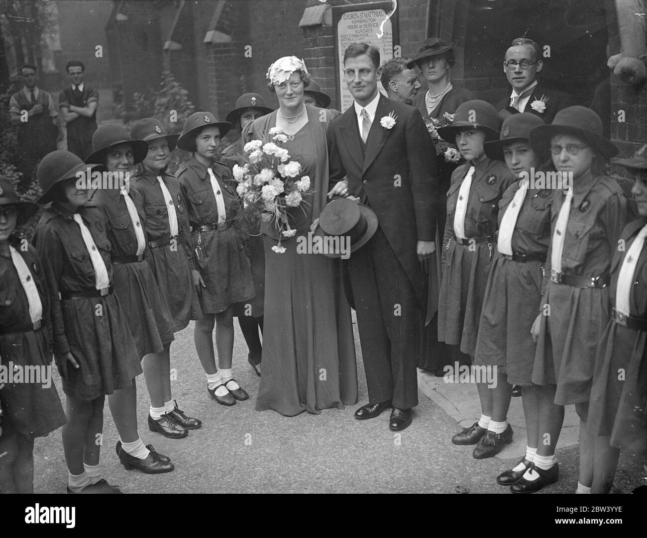 Early morning wedding at London church . Brides girl guides formed guard of honour . The key unusually early hour was chosen for the wedding at St Matthias Church , Earl's Court , of Mr R A Skelton , a British museum official , and Miss M K Macleod . A guard of honour was provided by the 11 Holborn Girl Guides of who the bride is captain . Photo shows , the bride and groom leaving the church through the guard of honour of Girl Guides . 24 September 1936 Stock Photo