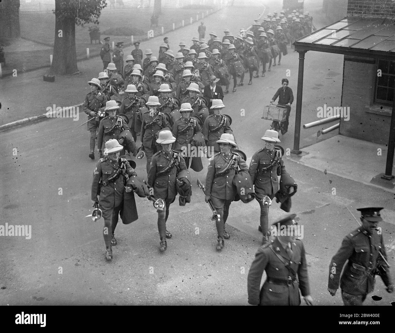 3rd carabiners inspected before leaving Hounslow for India . The 3 Carabiners ( C Squadron ) left Hounslow barracks to go to India . Inspection at the parade before departure was made by Major Shepley - Sheply . Photo shows , men of the 3 Carabiniers leaving Hounslow barracks wearing sun helmets. 23 September 1936 Stock Photo