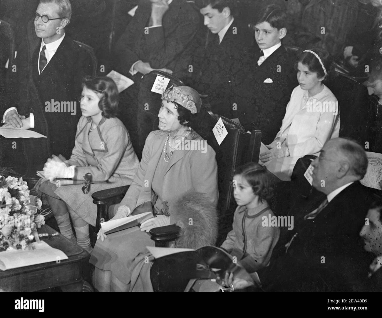 The Queen took her daughters, Princess Elizabeth and Princess Margaret Rose, to the Coronation Concert for Children at the Central Hall, Westminster. Photo shows: the Queen and Princess Elizabeth listening to the concert. 6 April 1937 Stock Photo
