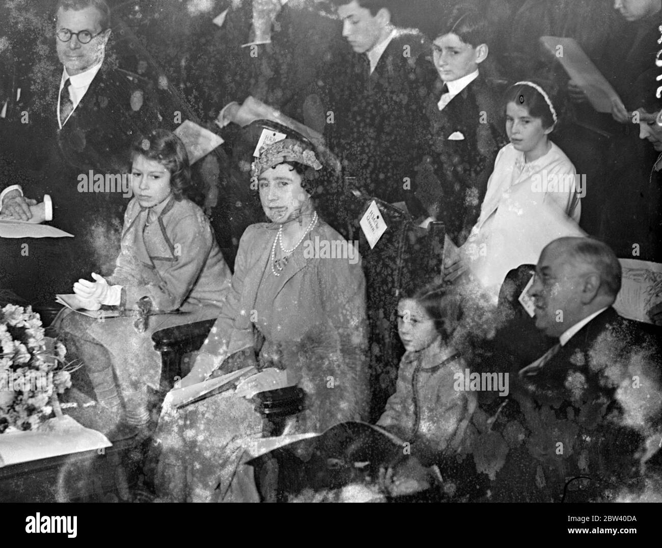 The Queen took her daughters, Princess Elizabeth and Princess Margaret Rose, to the Coronation Concert for Children at the Central Hall, Westminster. Photo shows: the Queen and Princess Elizabeth listening to the concert. 6 April 1937 Stock Photo