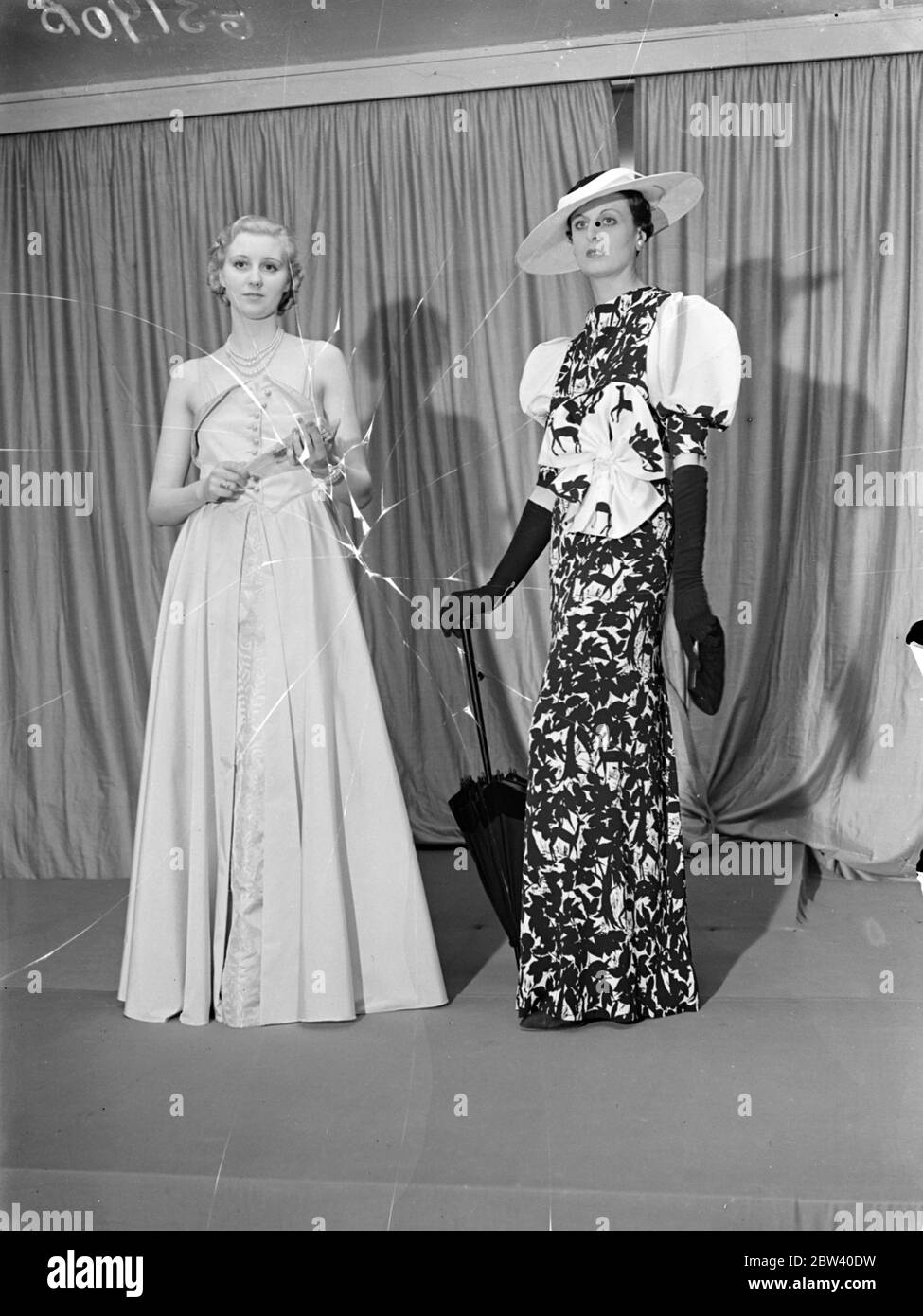 Coronation gowns shown at the London Exhibition. Beautiful gowns which will be seen during the Coronation season were shown at the Coronation Exhibition by British dress designers which Princess Beatrice opened in the Great Room at Grosvenor House, Park Lane. The Exhibition is being held in aid of the Sunshine Home for Blind Babies. Photo shows:Two creations for the State Ball at Buckingham Palace and the Royal enclosure at Ascot. On left is Parchement gold silver gown for the State Ball, and on right a black and white creation for Ascot. Both designs are by Reville. 7 April 1937 Stock Photo