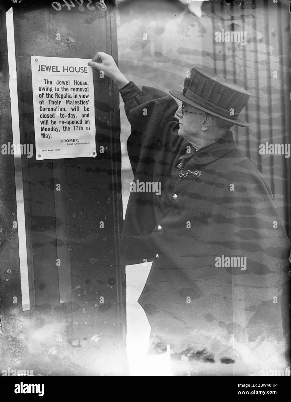 Wakefield Tower closed as Crown Jewels are removed for Coronation. Owing to the removal of the Crown Jewels for the Coronation, the Wakefield Tower at the Tower of London is being closed to the public until the middle of May. Photo shows: a Yeoman Warden pinning up the notice announcing the closing of the Jewel House at the Tower. 26 April 1937 Stock Photo
