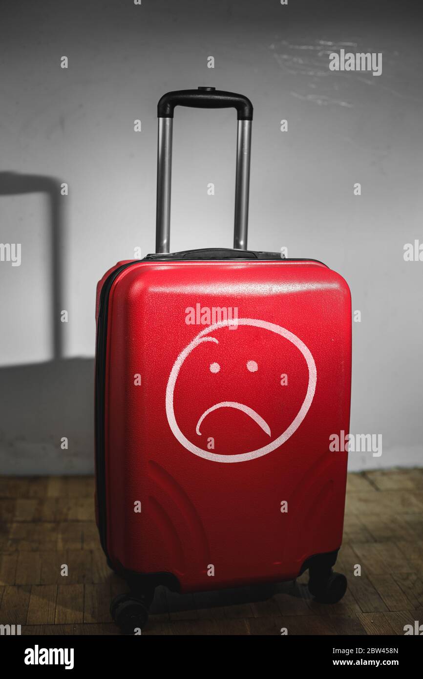 Red suitcase in home with sad smile inscription. Stay home COVID-19 no  traveling concept Stock Photo - Alamy