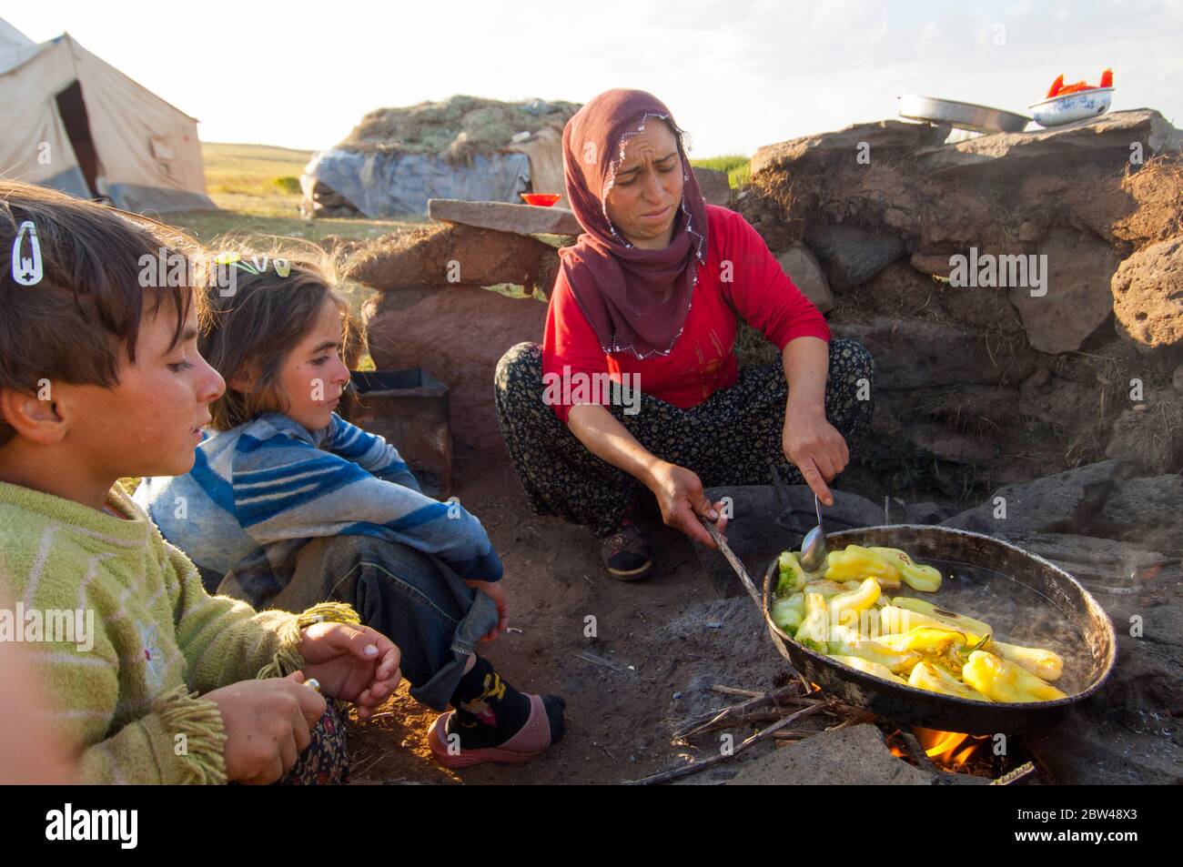 Asien, Türkei, Provinz Bingöl, Frau vom Stamm der Beritan-Nomaden an  Feuerstelle beim Zubereiten von Essen auf einer Hochweide in den Serafettin-Berg Stock Photo
