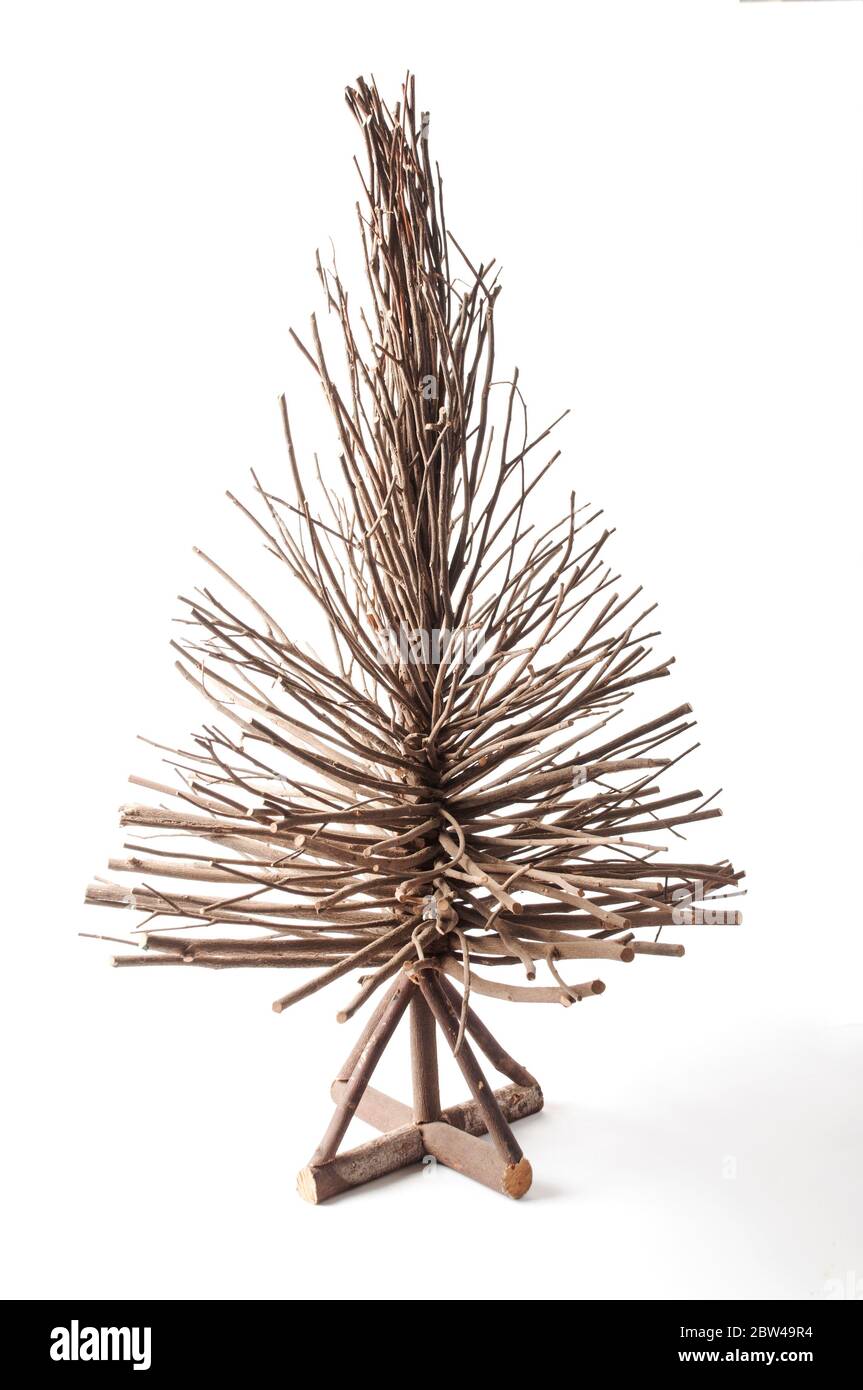 A wooden brown pointed tree, hand made of dried sticks, with a cross base. Resembles a christmas tree or conifer. Studio shot on white background Stock Photo