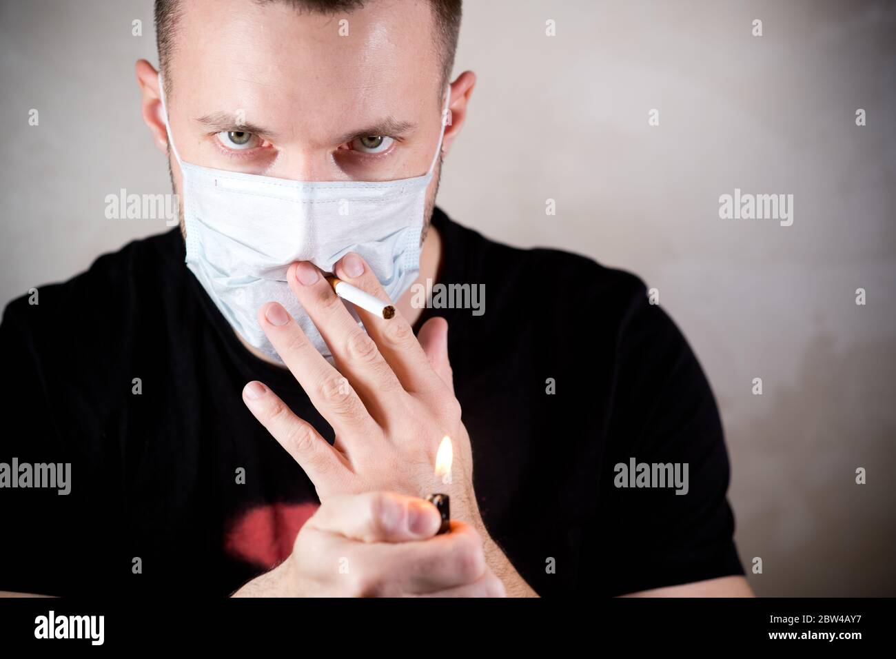 a man in a medical protective mask with a sad look about to smoke