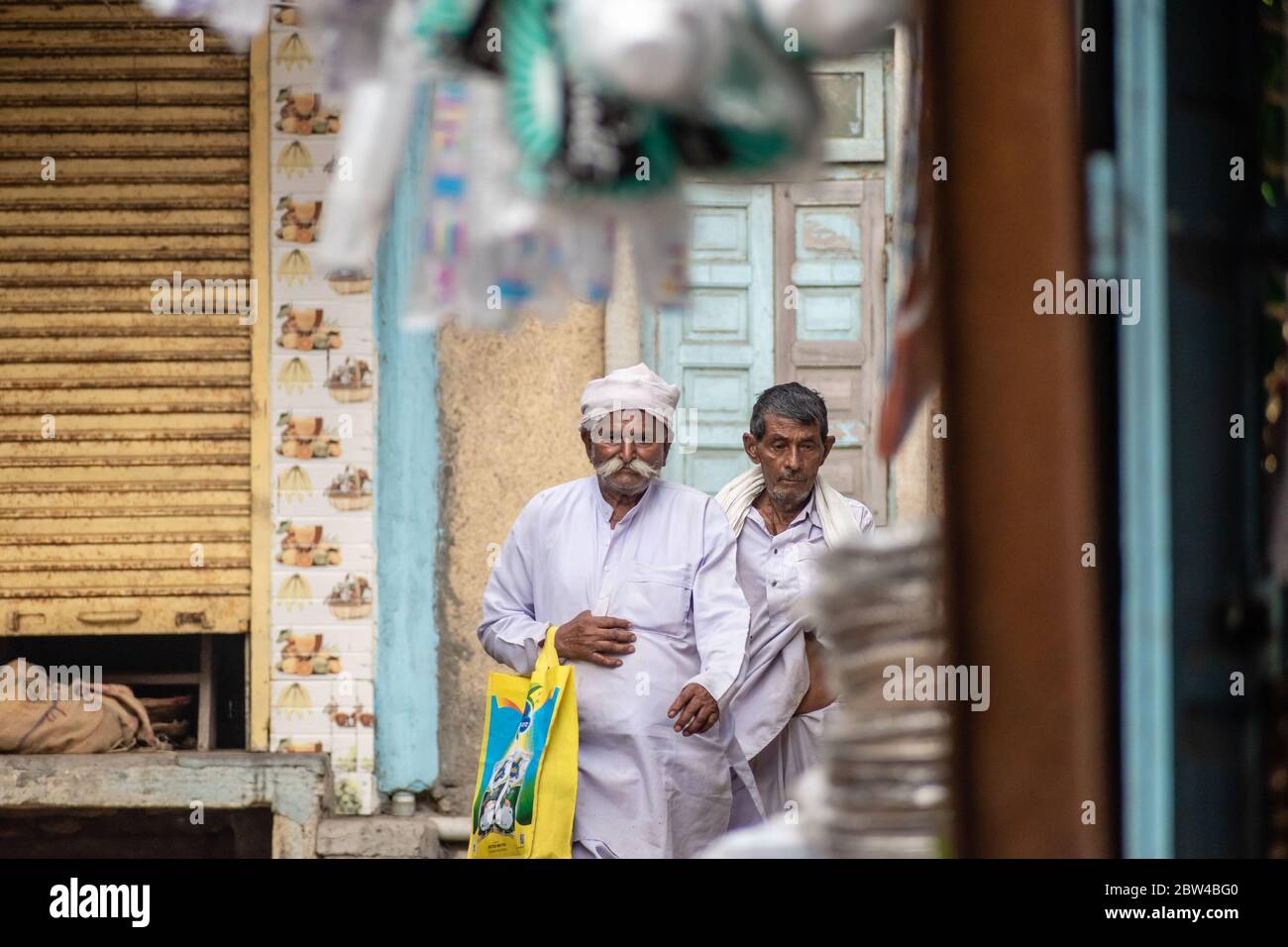 Somnath, Gujarat, India - December 2018: An elderly man with a white mustache wearing white, ethnic clothes walk in an alley in the old town. Stock Photo