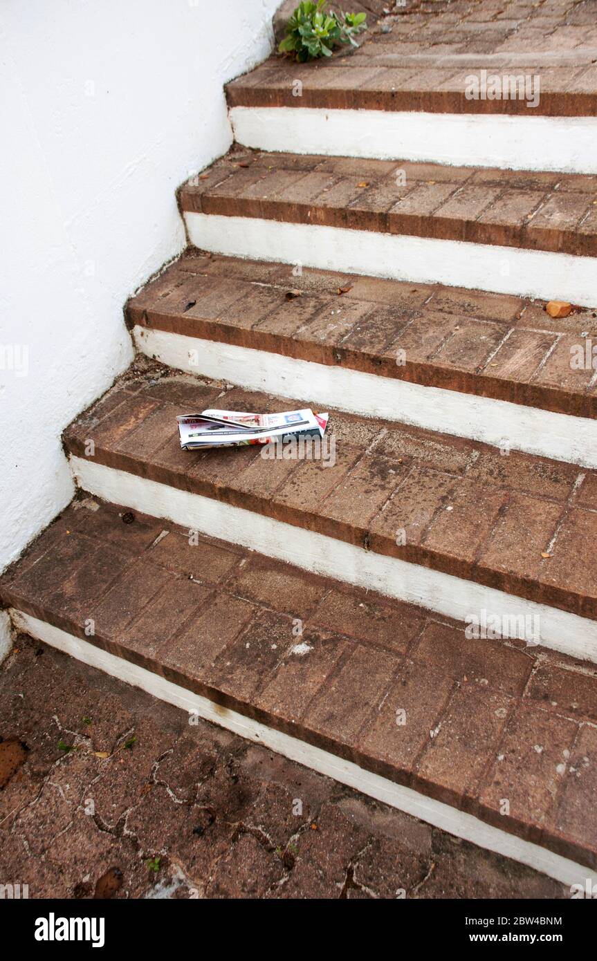 A discarded newpaper lying on some brick steps Stock Photo