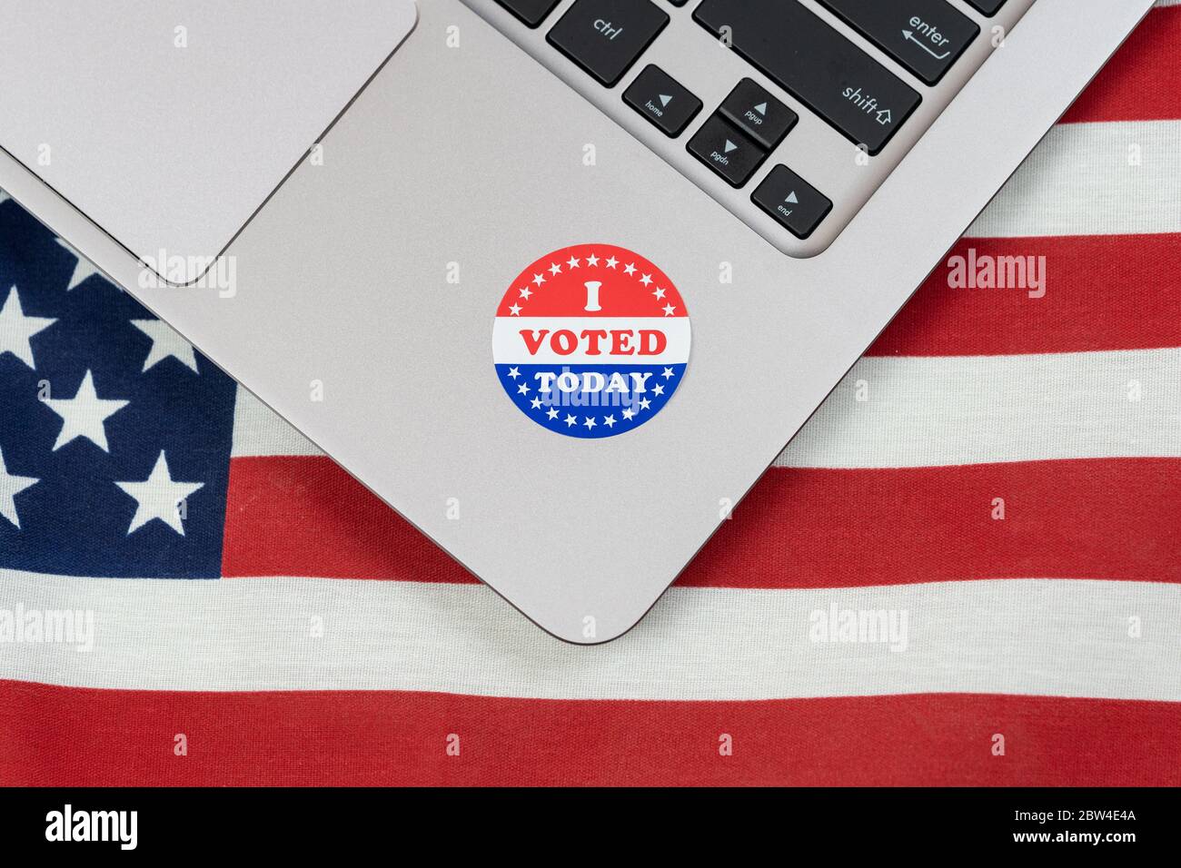 I Voted Today sticker on a laptop computer with the US flag behind for the concept of the controversy over online and mail in voting in the United Sta Stock Photo