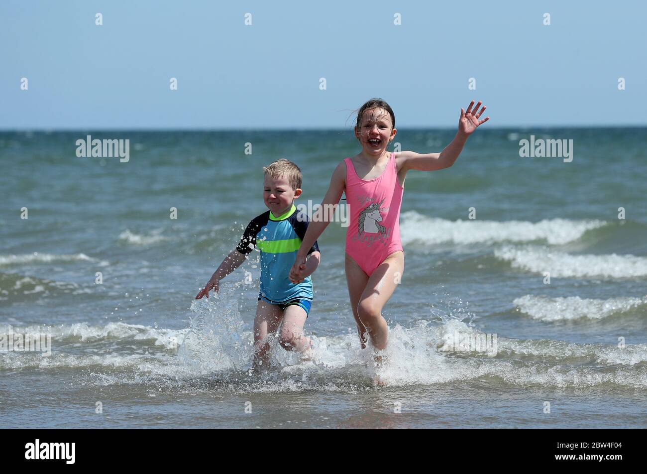 Four year old Cian Walshe, four, and his sister Ella, eight, play in the sea off Portmarnock Beach, Dublin, as the warm weather continues. Picture date: Friday May 29, 2020. The dry sunny weather is set to continue over the June bank holiday weekend, with temperatures forecast to hit 25C in some areas. See PA story WEATHER Sun Ireland. Photo credit should read: Brian Lawless/PA Wire Stock Photo