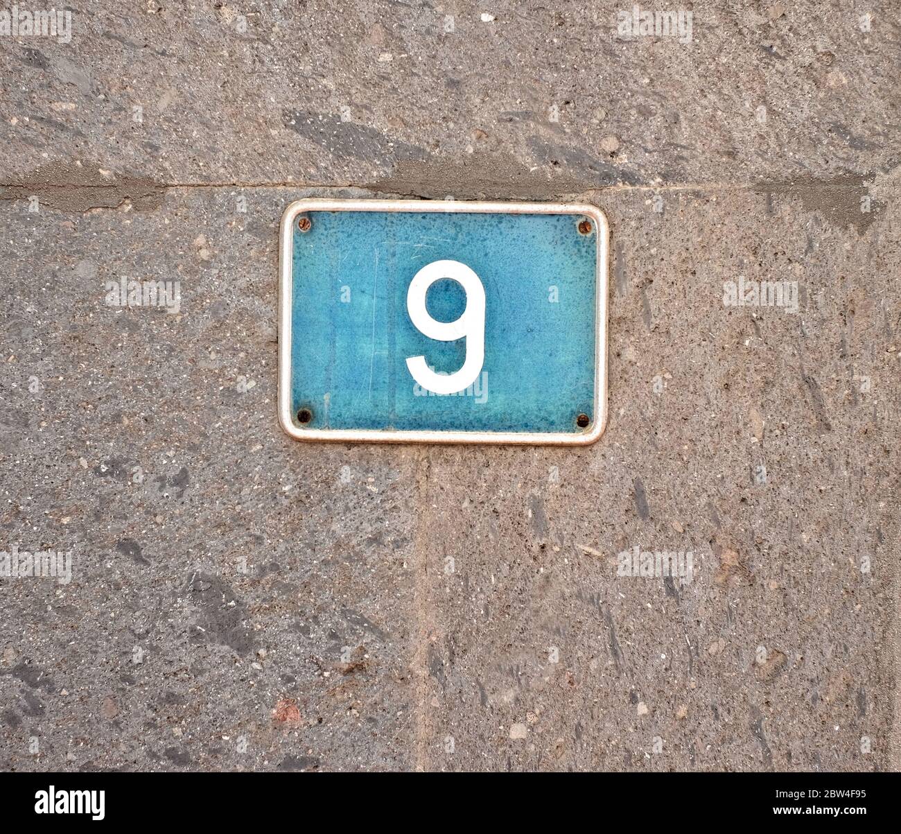 9, nine - light blue plate on gray stone surface. Stock Photo