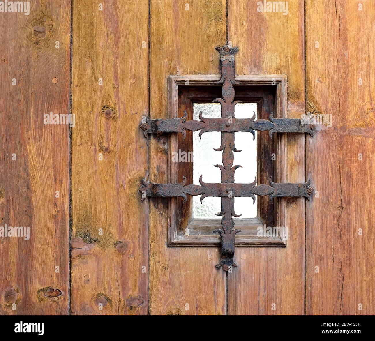 Vintage timber door with a small window and cast iron decorative element. Stock Photo