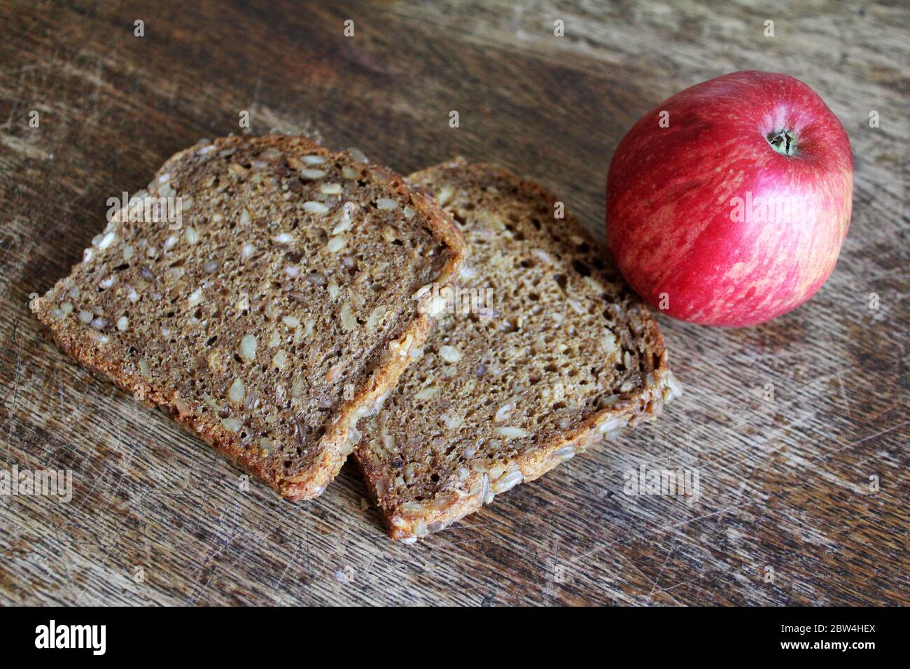 Slices of dark bread with corn and a red apple on a kitchen table Stock Photo