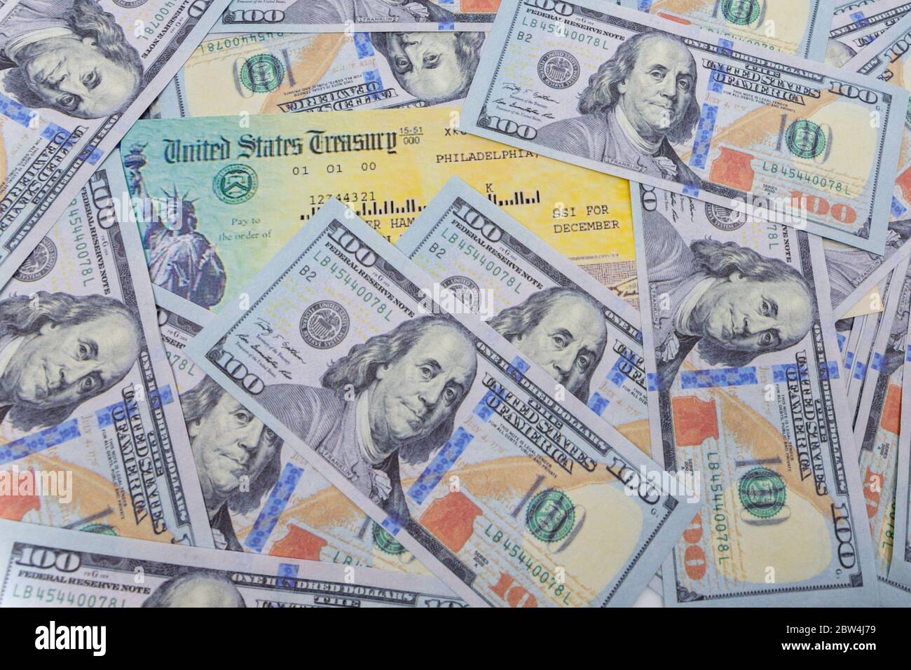 Stack of 100 dollar bills with coronavirus stimulus payment check to show the virus payment to Americans. Concept IRS tax refund or coronavirus stimul Stock Photo