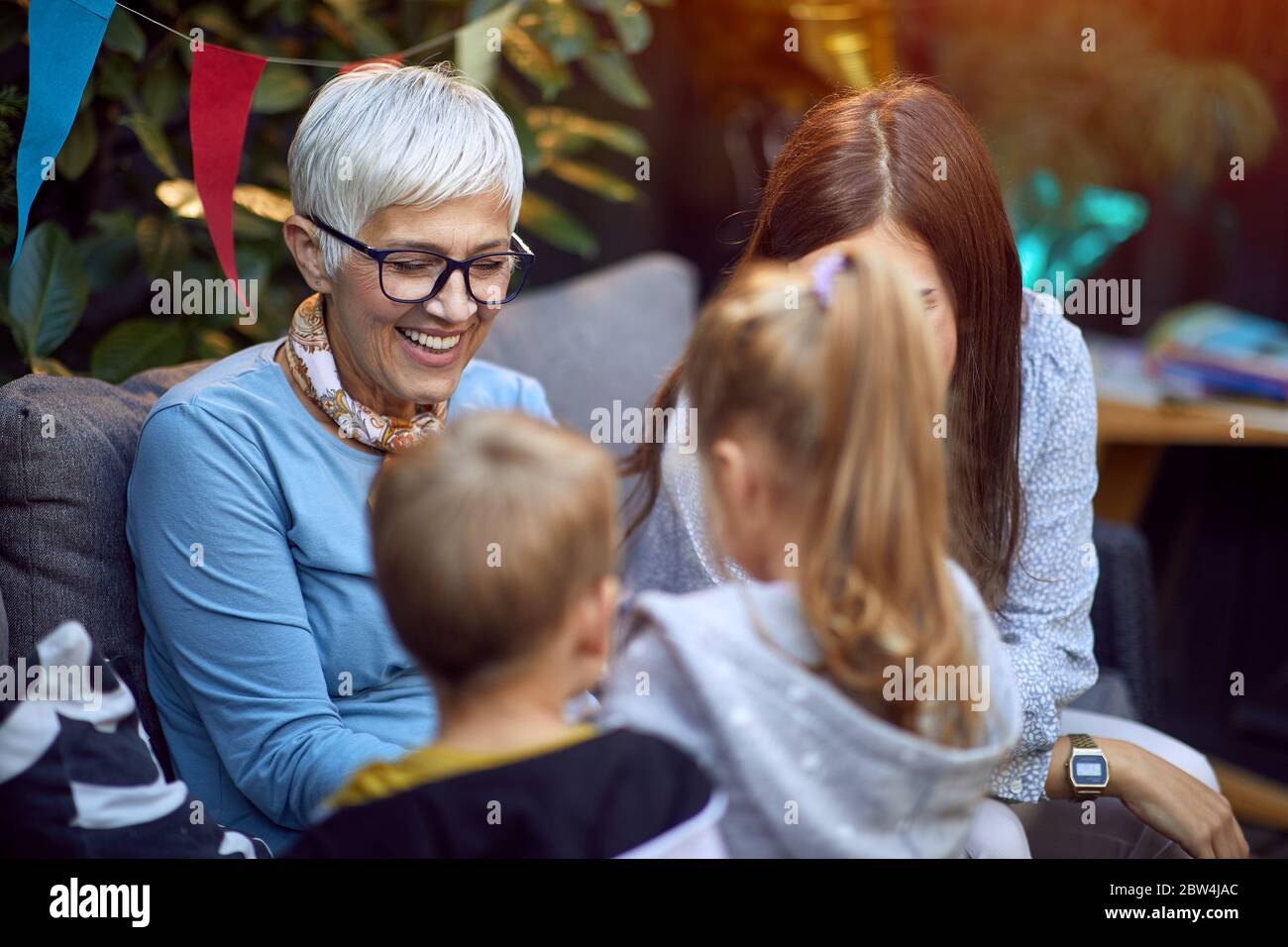 Smiling senior woman have fun with her grandchildren outdoor at home. Stock Photo