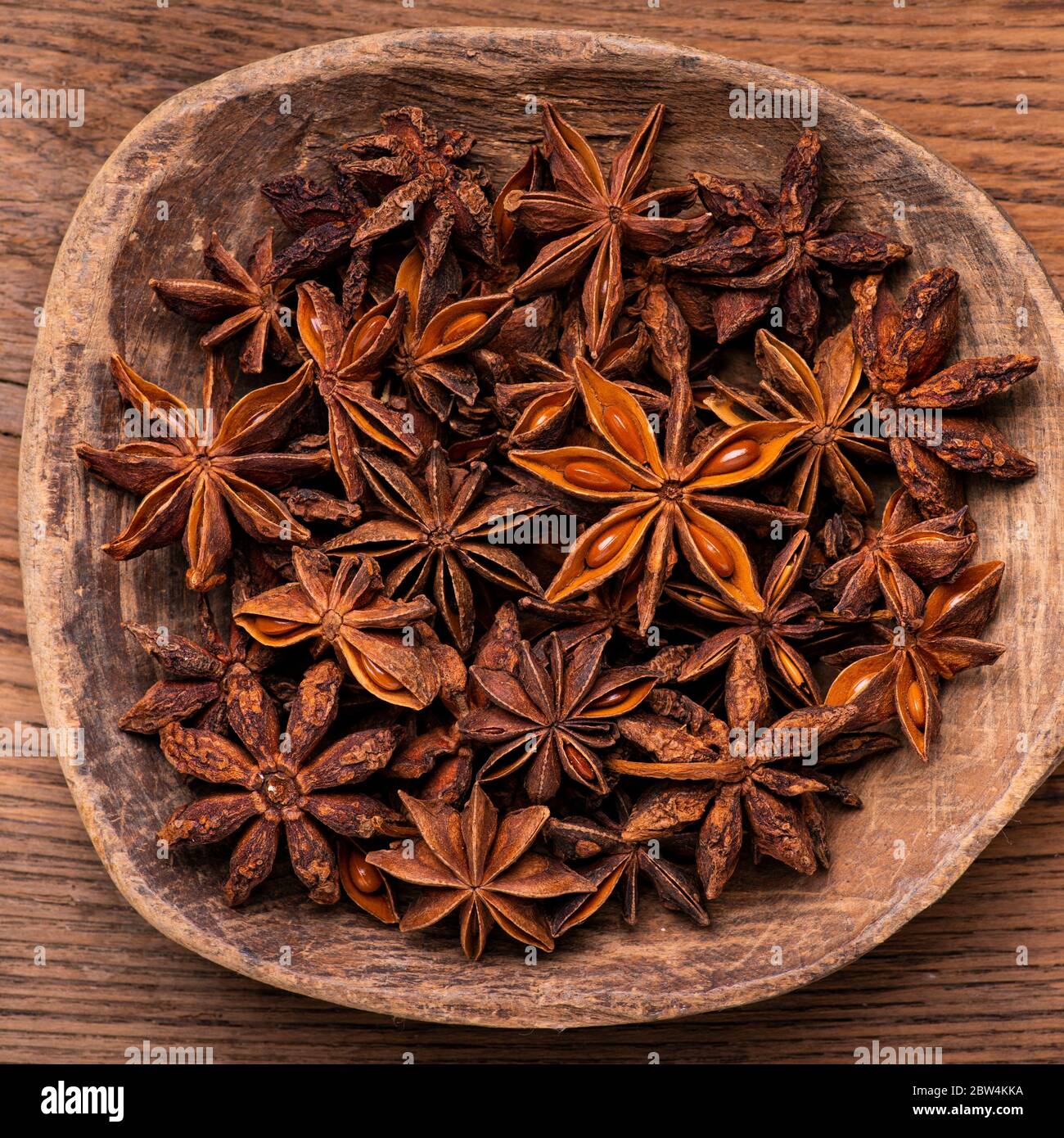 in the foreground, with a top view, a pile of star anise in the old wooden bowl Stock Photo