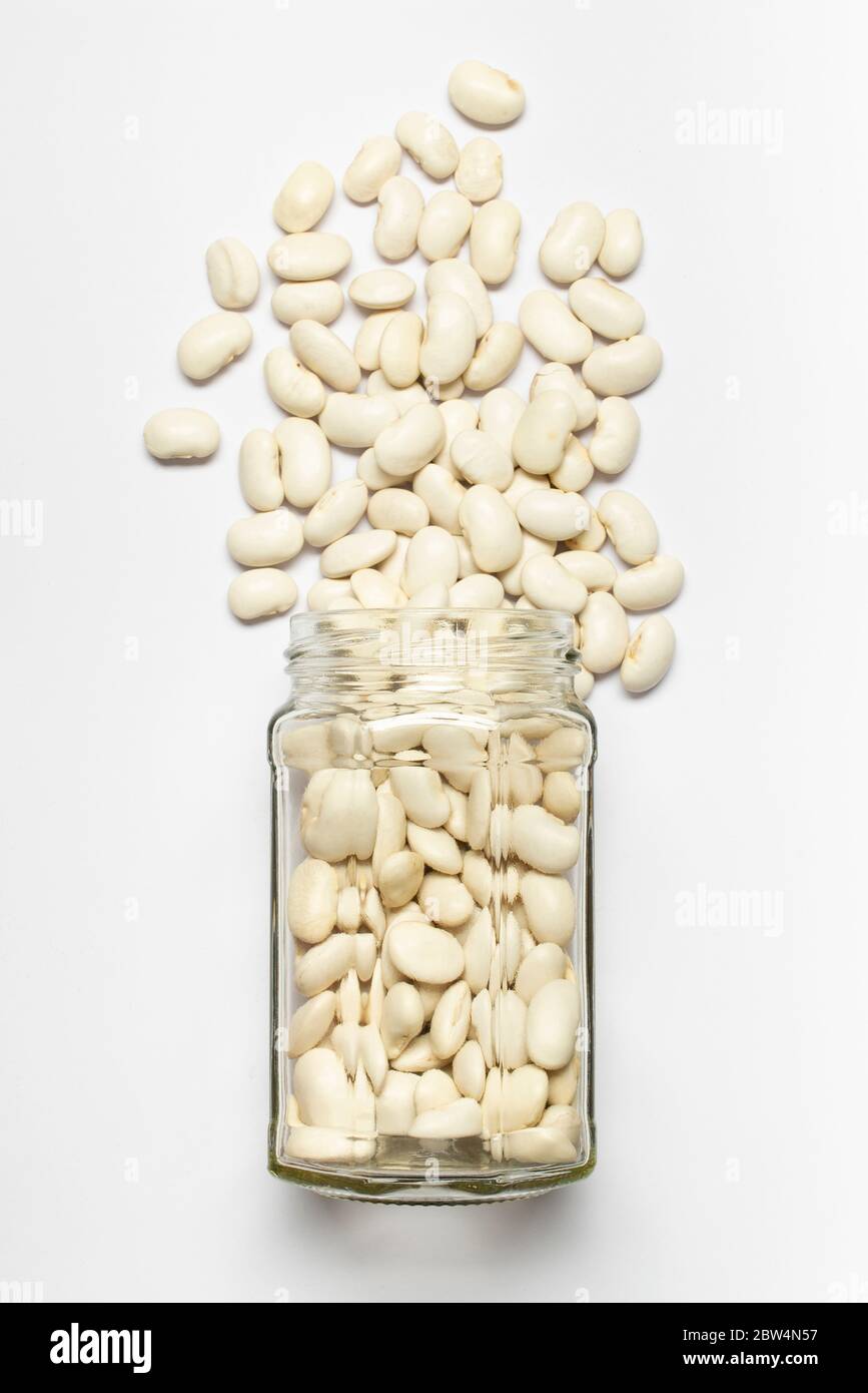 glass jar with dried Spain beans in the foreground, top view, isolated