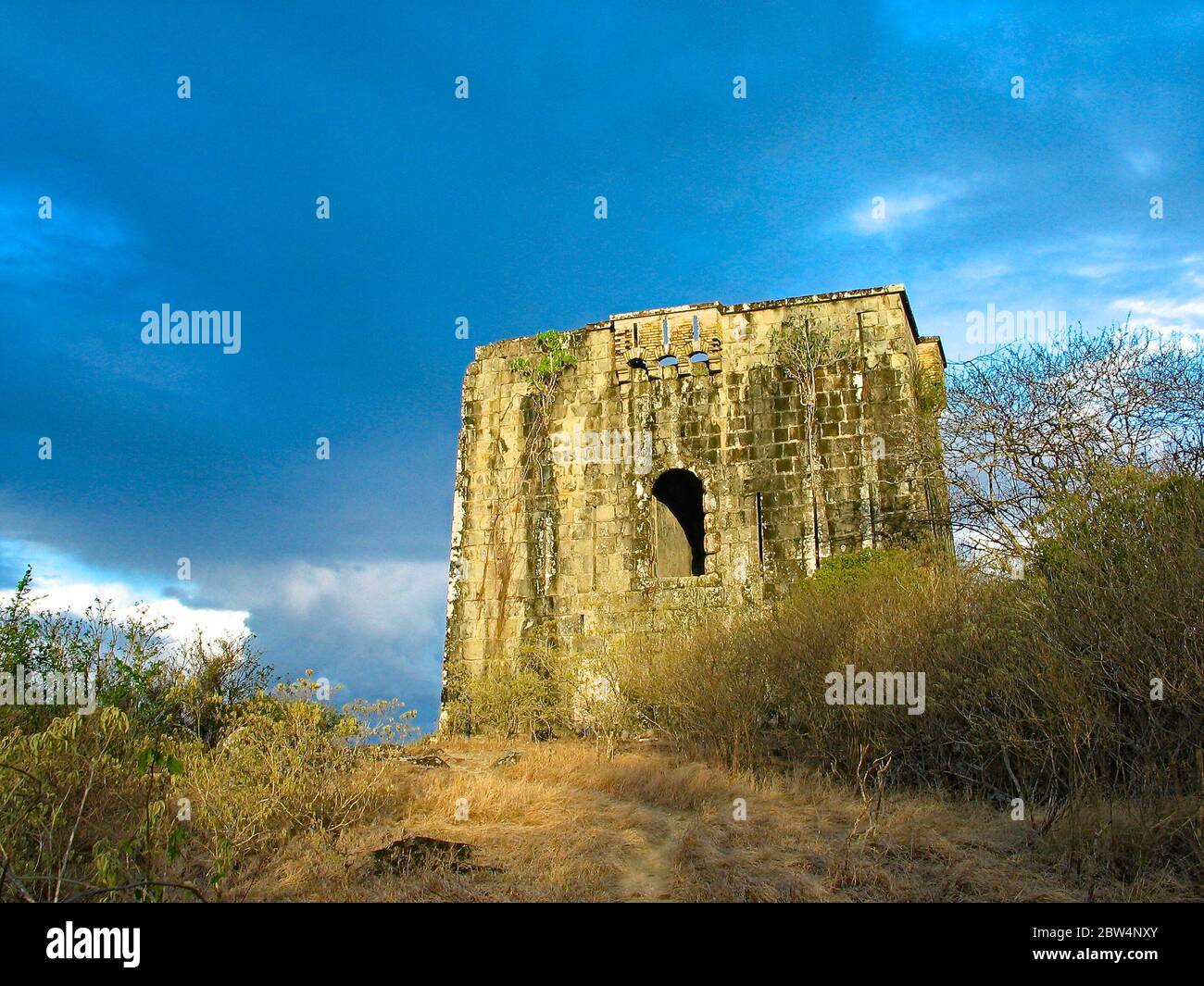 Ruins of an old tower on the hill, dark menacing sky background. Stock Photo