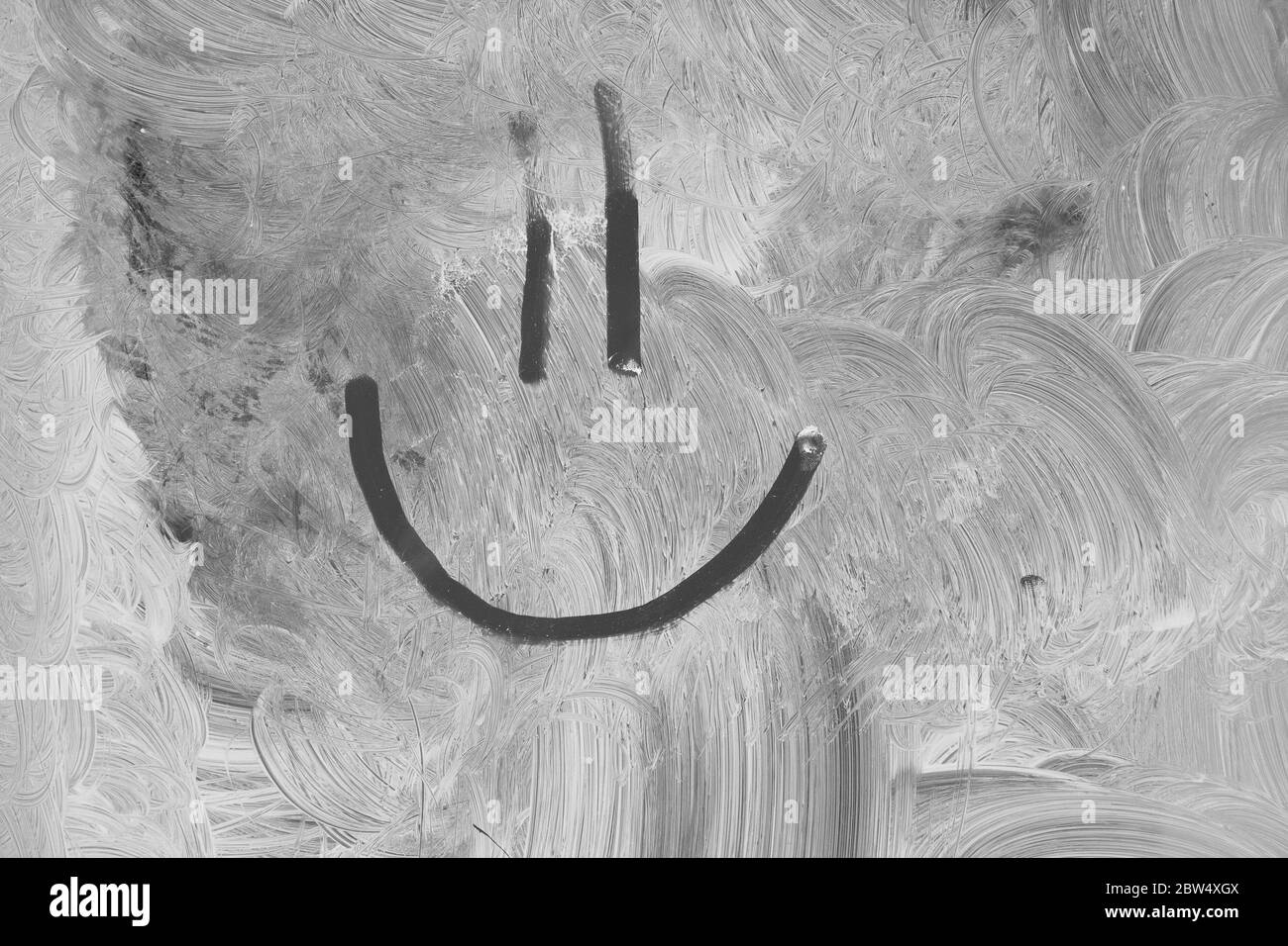 Closeup of a smiley face drawn on a whitewashed window. Stock Photo