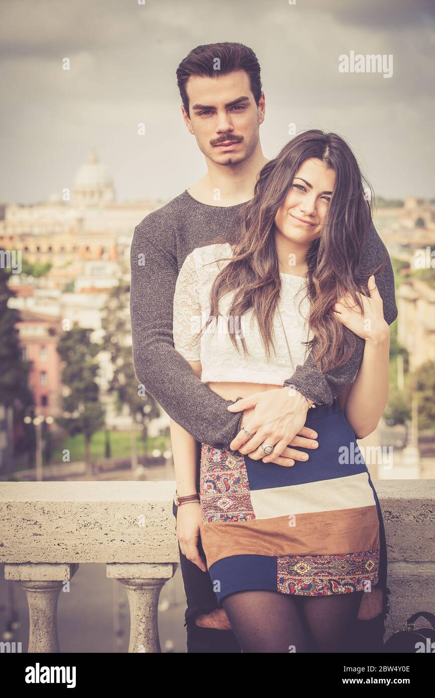 Holiday in Rome. Beautiful lovely young italian couple embracing outdoors. A couple, young man and a woman outdoors, is embracing on a terrace in the Stock Photo