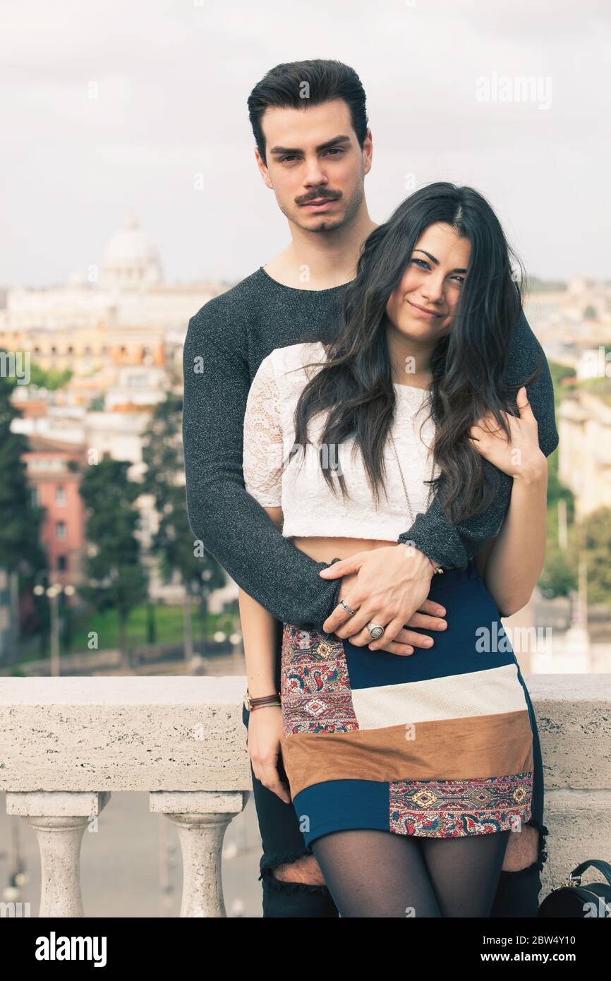 Holiday in Rome. Beautiful lovely young italian couple embracing outdoors. A couple, young man and a woman outdoors, is  on a terrace in the historic Stock Photo