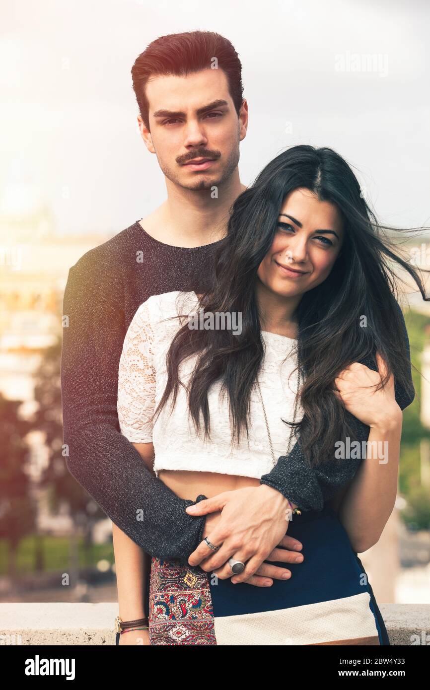 Holiday in Rome. Beautiful lovely young italian couple embracing outdoors. A couple, young man and a woman outdoors, is embracing on a terrace in the Stock Photo