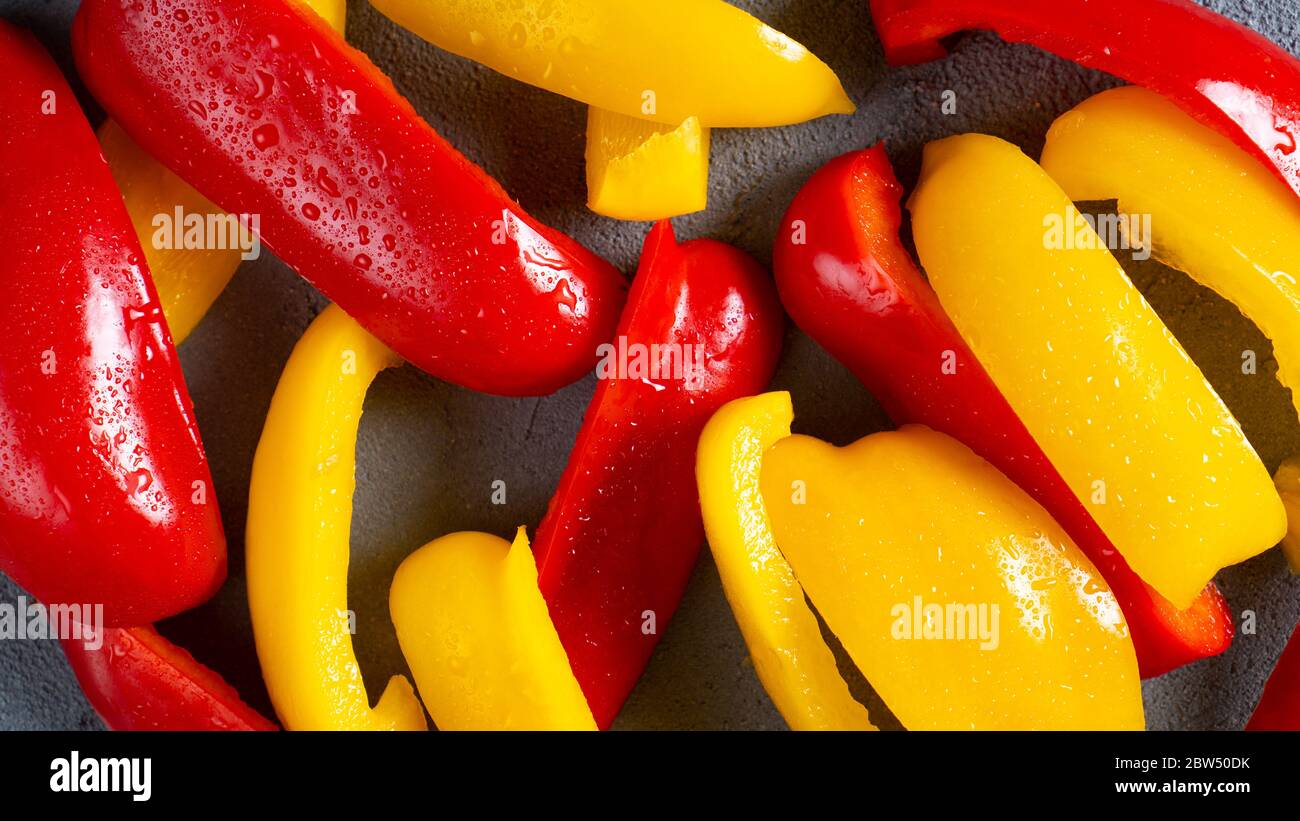 Sliced sweet bell pepper for healthy on dark background. Fresh washed slices of bellpepper. Red and yellow peppers Stock Photo