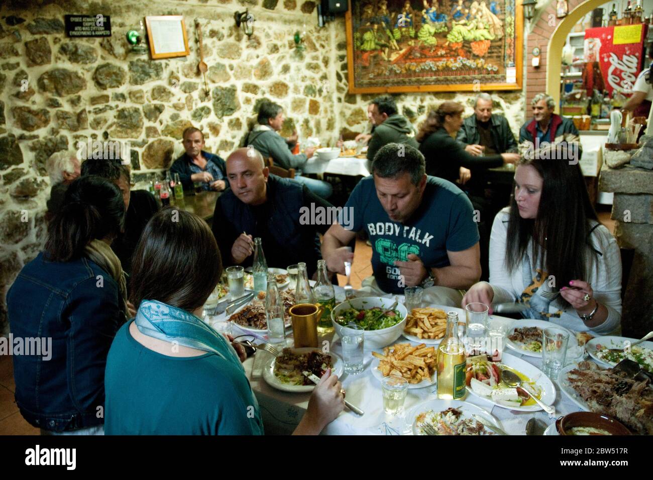 A group of Greek friends eating dinner at a local village restaurant in the town of Profitis Ilias on the island of Samothraki, Thrace, Greece. Stock Photo