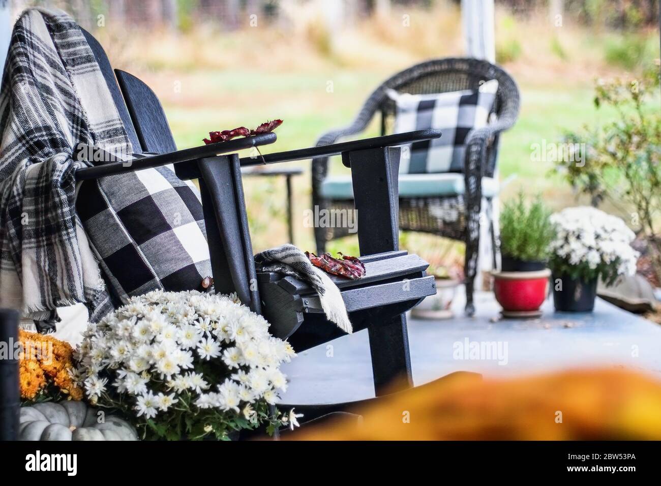 Adirondack rocking chair with traditional style buffalo check blanket and pillows on a porch or patio decorated for autumn with heirloom gourds and wh Stock Photo Alamy