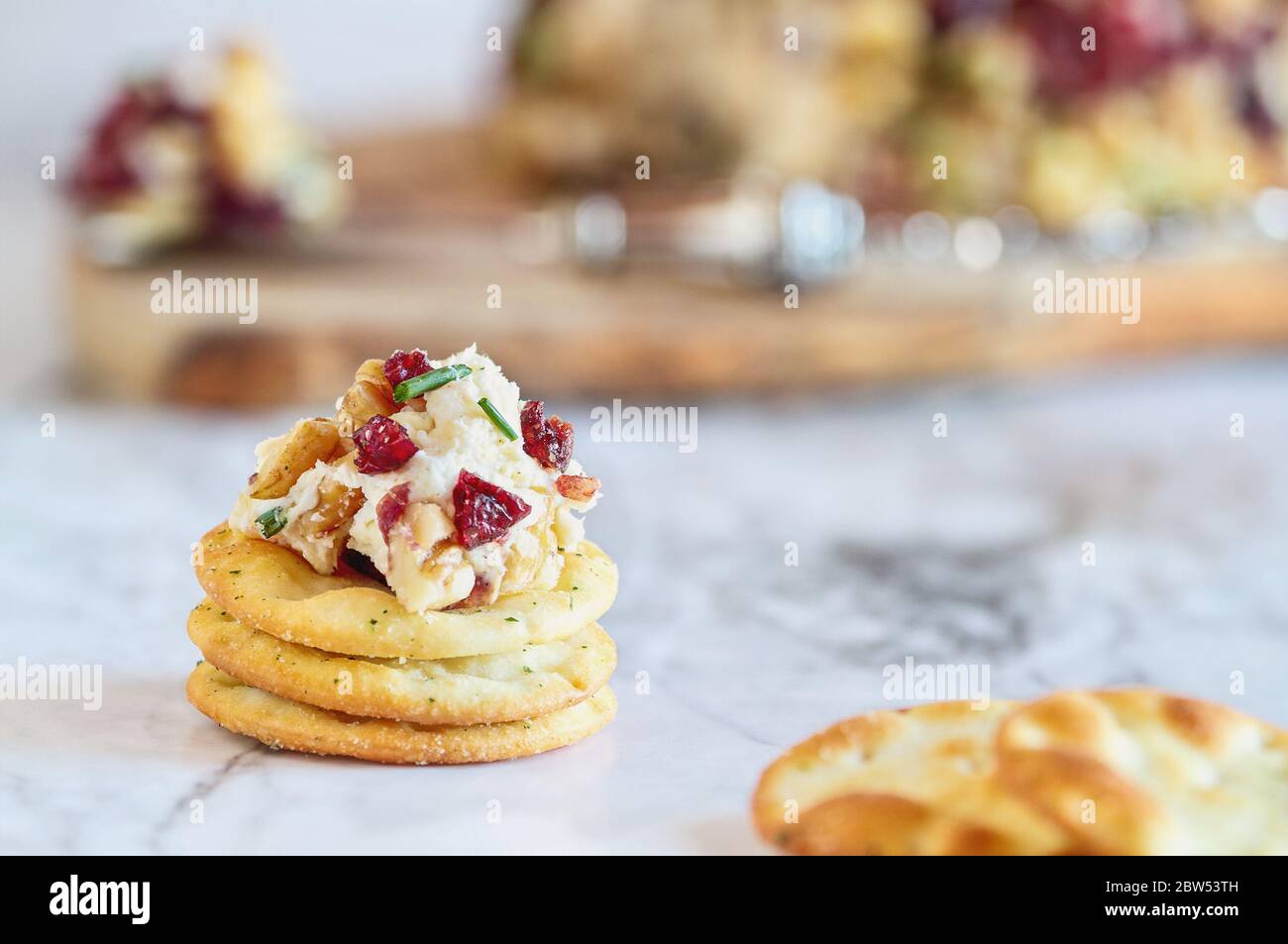 Fresh homemade cranberry cheese spread made with cream cheese, white cheddar, dried cranberries, walnuts, and chive over marble table. Selective focus Stock Photo