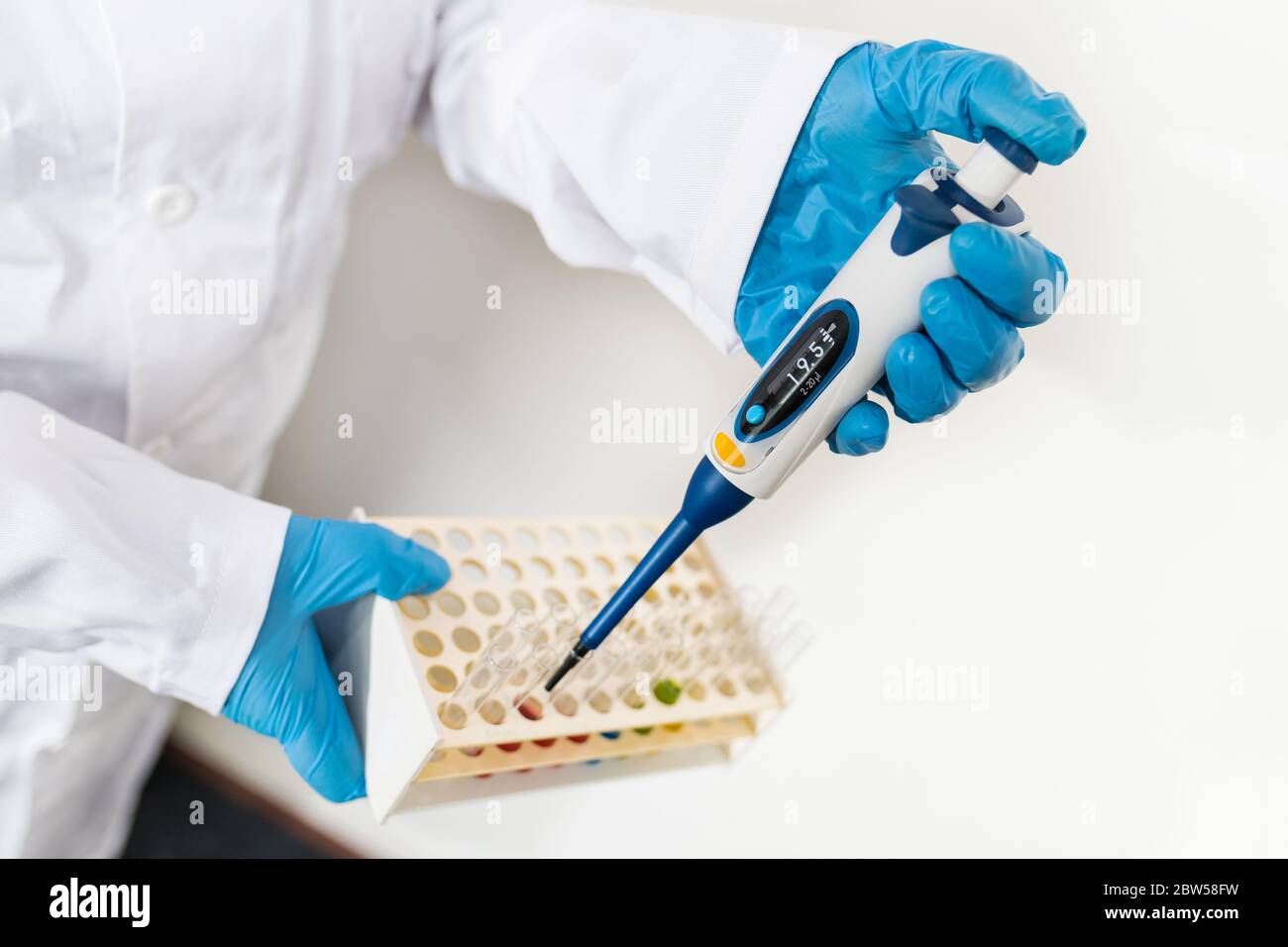 Scientist with pipette in hand dripping fluid to glass test tubes in