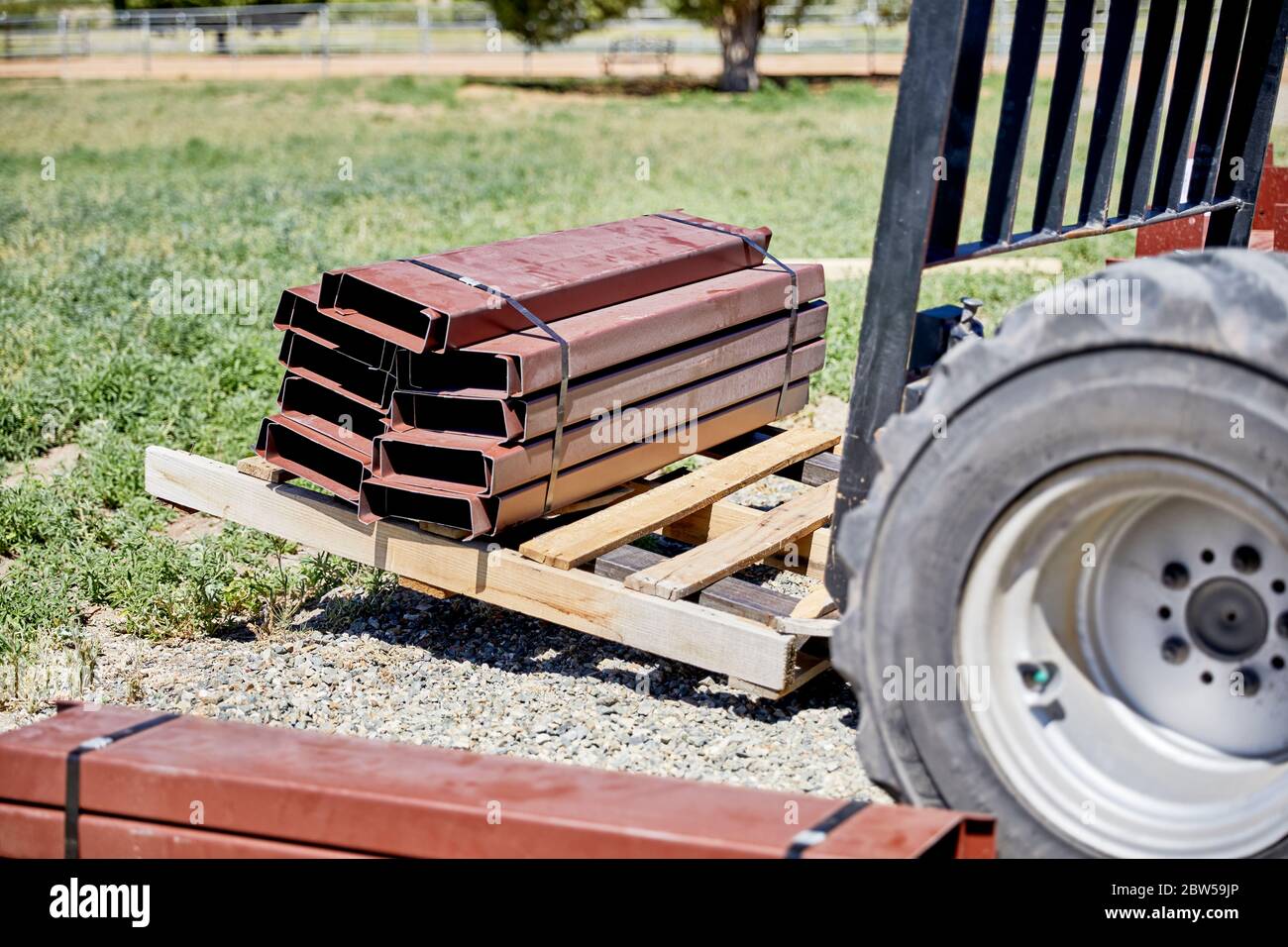 Fork lift on gravel driveway moving steel building supplies on a pallet