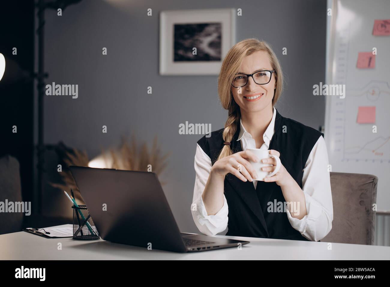 Business lady drinking coffee while working on laptop Stock Photo