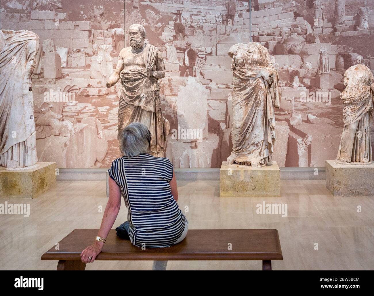 Tourist viewing the statue of the Greek philosopher Plutarch or Plato in the Delphi Archaeological Museum, Greece Stock Photo