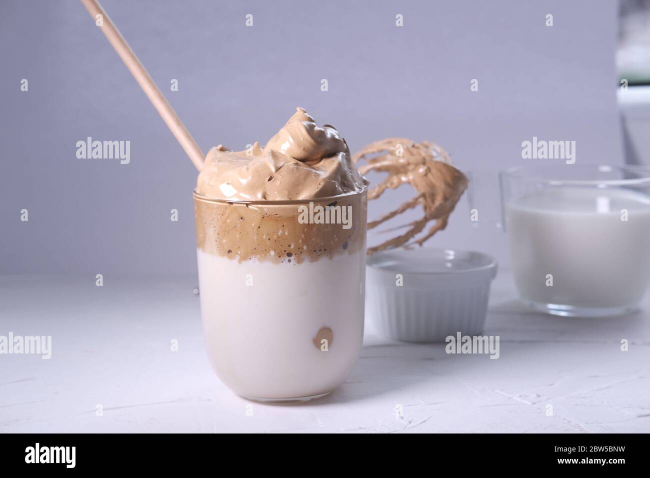 Dalgona coffee with whipped coffee and milk in background. Iced and fluffy Korean coffee Stock
